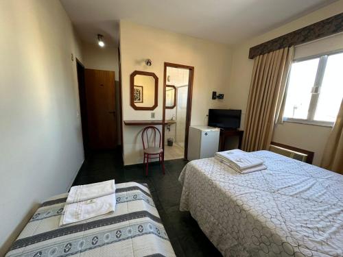 a hotel room with two beds and a mirror at Suíte no centro de Angra dos Reis - 13 in Angra dos Reis