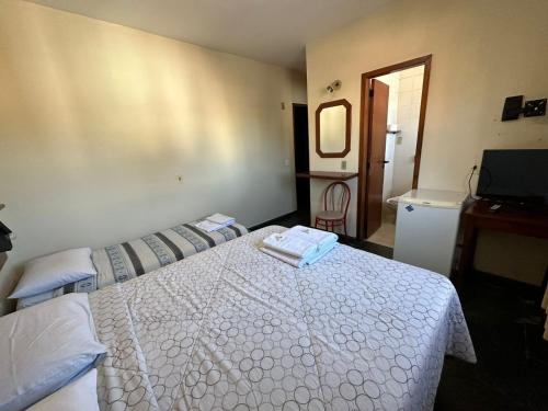 a bedroom with a white bed and a television at Suíte no centro de Angra dos Reis - 13 in Angra dos Reis