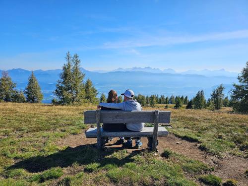 a man and a woman sitting on a bench at Gerlitzen-Apartments in Kanzelhöhe