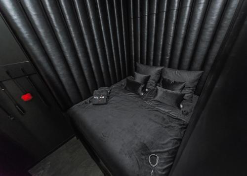 Cama pequeña con sábanas y almohadas negras en Eclipse Red Room, en Bielsko-Biala