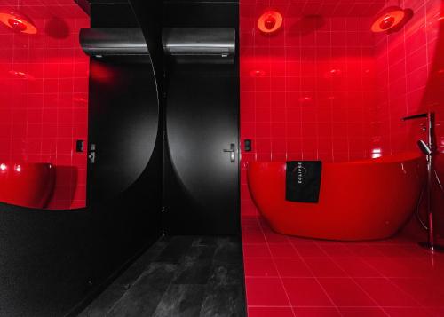 Baño rojo con bañera roja y azulejos rojos en Eclipse Red Room, en Bielsko-Biala