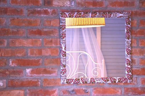 a mirror on a brick wall with a chair in a window at Hotel Anchor in Sinemorets