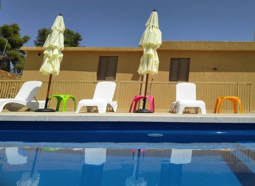 a group of chairs and umbrellas next to a swimming pool at אשל ציפורה in Arad