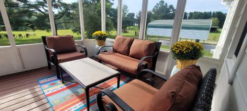 a screened in porch with chairs and a table at Meadow Farm in Holly Springs, NC in Holly Springs