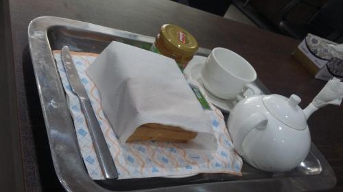 a tray with a sandwich and a tea pot at Dove Inn Hotel in Lahore