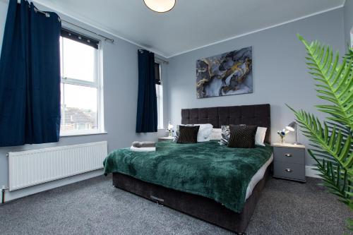 Newly Renovated Perfect Family Home in Nottingham في نوتينغهام: غرفة نوم بجدران زرقاء وسرير ببطانية خضراء