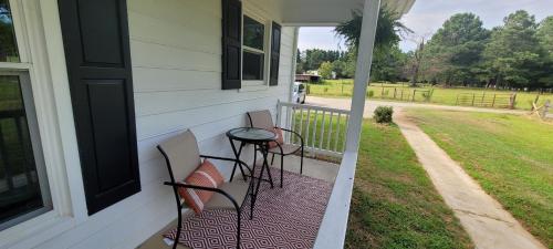 a porch with chairs and a table on a house at Meadow Farm in Holly Springs, NC in Holly Springs
