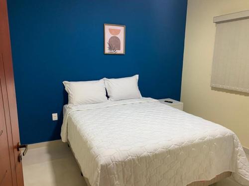 a bedroom with a bed with a blue wall at Pousada Jaguary in Bragança Paulista