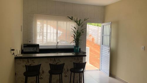 a kitchen with a counter with chairs and a sink at Pousada Jaguary in Bragança Paulista