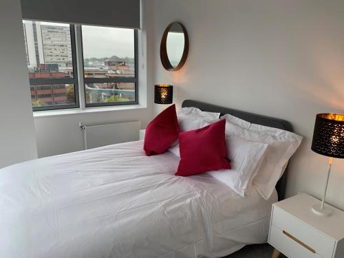 een slaapkamer met een wit bed en 2 rode kussens bij Bracknell Stunning 2 Bedroom and 2 Bathroom Apartment in Bracknell