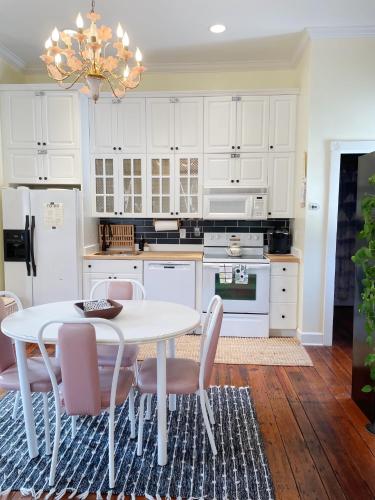 a kitchen with white cabinets and a white table and chairs at Romantic 1885 Loft Steps from Pulaski Square in Savannah
