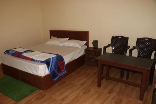 a bedroom with a bed and a table and two chairs at Kalika Hill Resort in Barkot