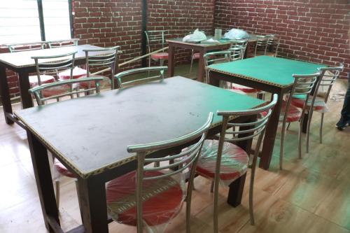 a group of tables and chairs in a room at Kalika Hill Resort in Barkot