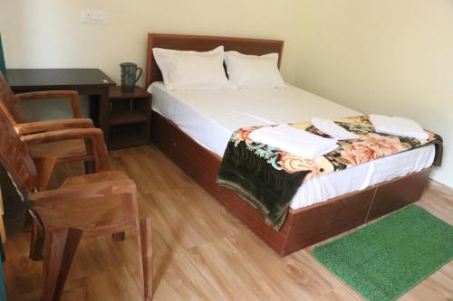 a bedroom with a bed and a desk and a chair at Kalika Hill Resort in Barkot
