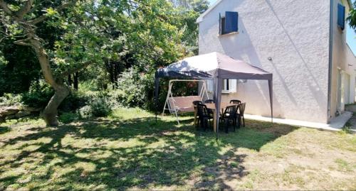 uma mesa e cadeiras debaixo de uma tenda num quintal em Gite Libecciu em Pietracorbara
