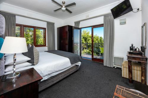 a bedroom with a bed and a tv and windows at Maartens Guesthouse in Cape Town