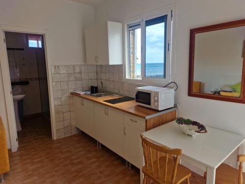 a kitchen with a microwave and a table and a window at Casa Carmen in Castillo del Romeral