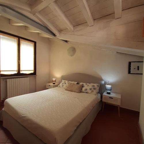sypialnia z dużym białym łóżkiem i 2 oknami w obiekcie Loft trabucco panoramico 4 camere 7posti letto vista lago e centro storico w mieście Salò