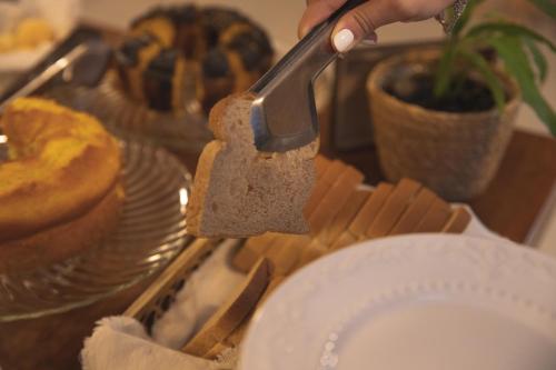 a person holding a spatula over a plate on a table at Pousada Calza - Vale dos Vinhedos - Bento Gonçalves in Bento Gonçalves