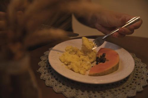 a person holding a fork and a plate of food at Pousada Calza - Vale dos Vinhedos - Bento Gonçalves in Bento Gonçalves
