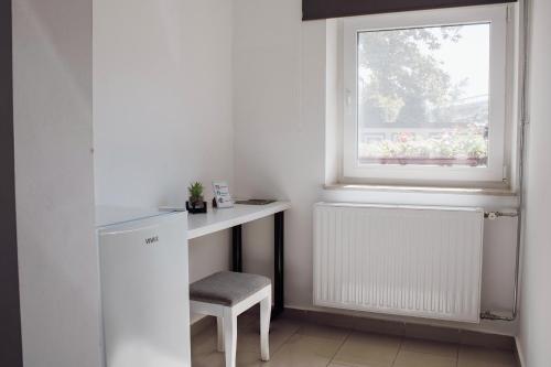 a white desk with a chair next to a window at Črni Baron Pension Black Baron in Maribor