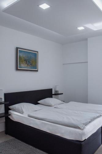 a white bedroom with a bed with a picture on the wall at Črni Baron Pension Black Baron in Maribor