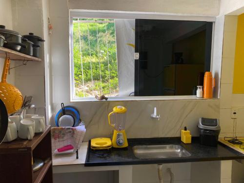 a kitchen counter with a sink and a window at Suítes Verano in Baía Formosa