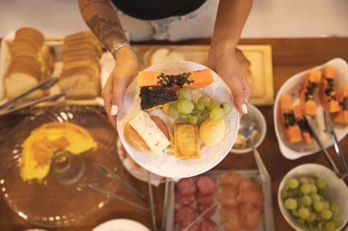 a person holding a plate of food on a table at Pousada Calza - Vale dos Vinhedos - Bento Gonçalves in Bento Gonçalves