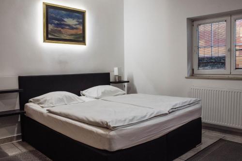 a bedroom with a bed with white sheets and a window at Črni Baron Pension Black Baron in Maribor
