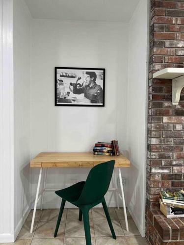 a desk with a green chair and a picture on the wall at Gator Haven in Gainesville