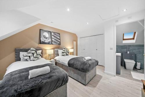 a large bedroom with two beds and a bathroom at Luxury House with Pool Table, Sky TV, Netflix, Fast Wifi, Garden & Free Parking by Yoko Property in Milton Keynes