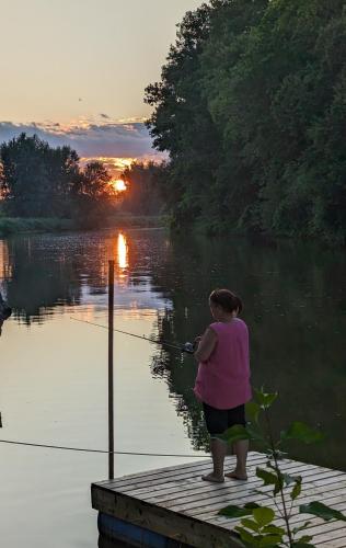 a woman standing on a dock holding a rod in the water at Pourvoirie Stéphane Marin in Maskinongé