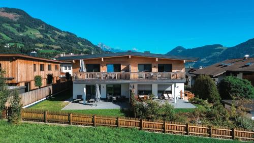 a house with a fence and mountains in the background at ISANORA - Garden Apartment with Private Whirlpool in Zillertal, presented by AlpenLuxus in Fügen