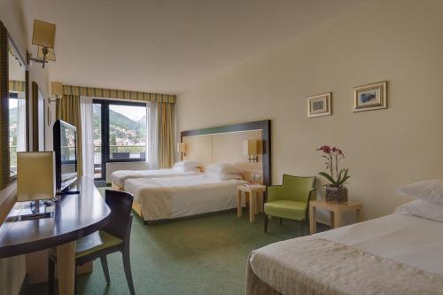 a hotel room with two beds and a table and chairs at Hotel Griso Collection in Malgrate