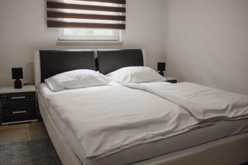 a bedroom with a bed with white sheets and pillows at Črni Baron Pension Black Baron in Maribor