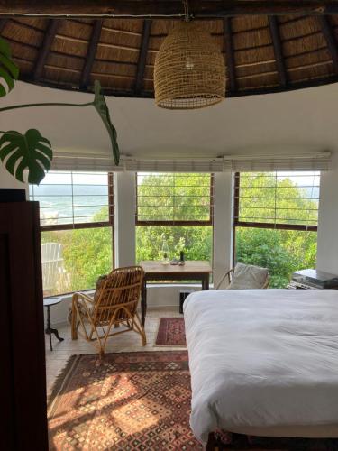 a bedroom with a bed and a desk and windows at Rondawel with sea view in Kleinmond