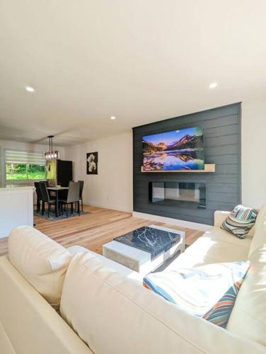 a living room with a white couch and a flat screen tv at The Lilac Bungalow in Kingston