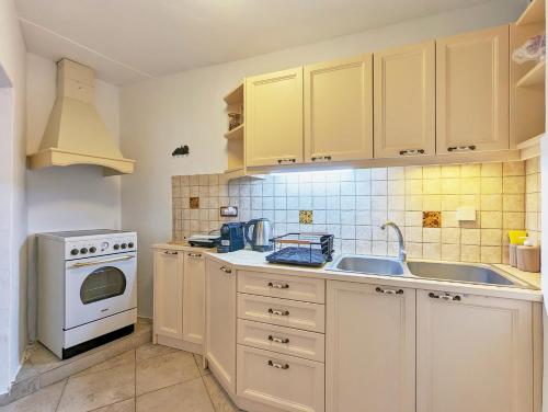 La cuisine est équipée de placards blancs, d'un évier et d'une cuisinière. dans l'établissement Thavma in Sifnos, à Apollonia