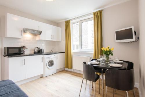 a kitchen and dining room with a table in a room at Chelsea Cloisters Serviced Apartments in London
