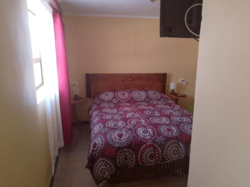1 dormitorio con 1 cama con colcha roja y blanca en sleep easy, en Coquimbo