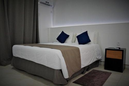 a bedroom with a large bed with blue pillows at Fenix Hotel Pouso Alegre in Pouso Alegre