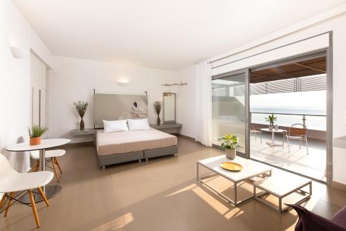 a bedroom with a bed and a table and chairs at Mare Dei Suites Hotel Ionian Resort in Skafidia