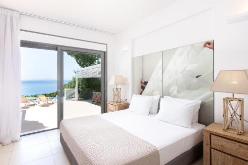 a bedroom with a bed and a view of the ocean at Mare Dei Suites Hotel Ionian Resort in Skafidia