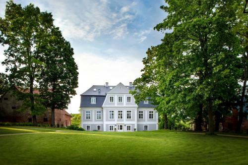 a large white house with trees on a lawn at Pałac Kamieniec in Polanica-Zdrój