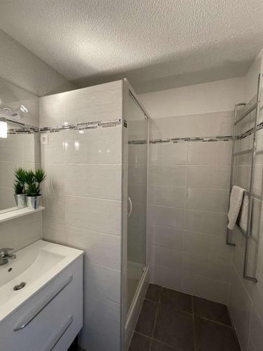 une salle de bain blanche avec une douche et un lavabo dans l'établissement Bel appartement au pied du marché noel, au Barcarès