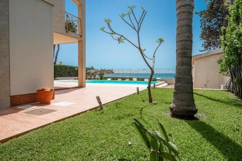 un patio con una palmera y una piscina en Villa Calliope Sea Beach, en Fontane Bianche