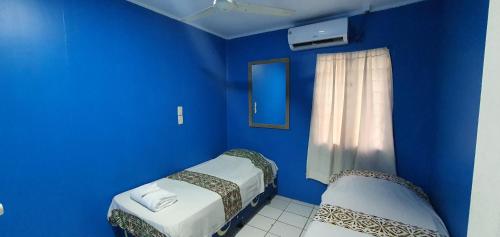 een blauwe kamer met 2 bedden en een raam bij Lynn's Getaway Guest House in Apia