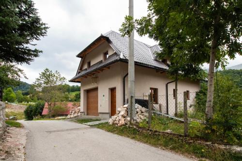 a small white house with a pole next to a road at Apartmani Jelenača in Sinanovići