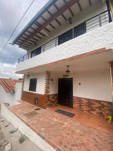 a white house with a black door and a brick patio at Casatoca House Zapatoca Lengerke in Zapatoca