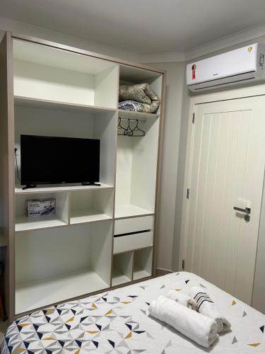 a bedroom with a bed and a tv and shelves at Apartamento Completo Próximo a Praia - Residencial Vieira in Florianópolis
